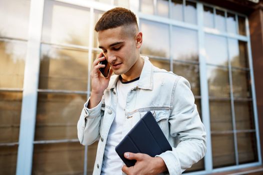 Young casual man walking on the city street and talking on the phone, close up portrait
