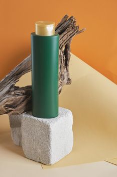 green bottle for shampoo or hair balm on a concrete podium on a wooden driftwood background, brown background, mock up cosmetic