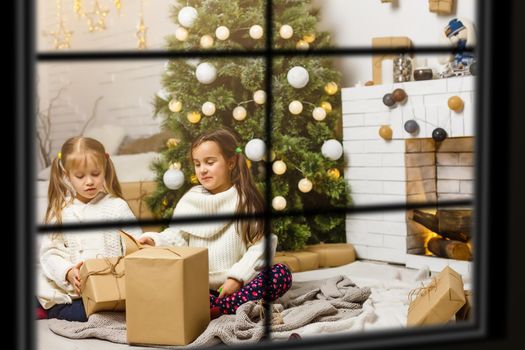 Big family with three children celebrating Christmas at home. Festive dinner at fireplace and Xmas tree. Parent and kids eating at fire place in decorated room. Child lighting advent wreath candle