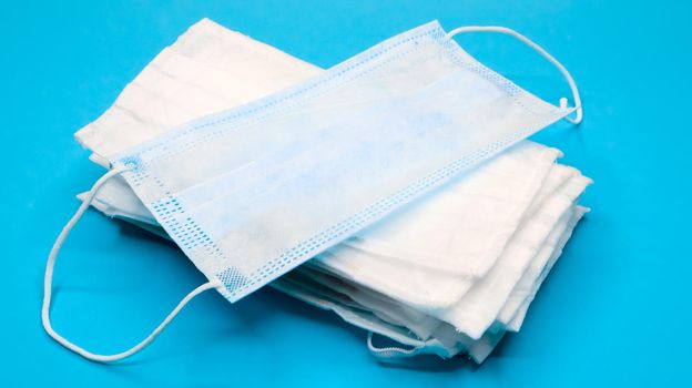 Coronavirus protection. Antiviral protective medical face masks with ear loops. Surgical mask background. Respiratory syndrome, coronavirus disease COVID-19. Many folded medical masks