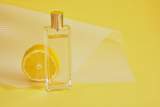 citrus scent, perfume with lemon scent concept, lemon slice and bottle of perfume on yellow background copy space