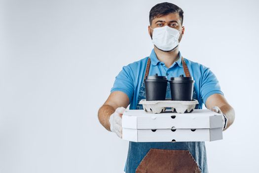 Delivery man in protective mask and medical gloves holding takeaway food. Compliance with the hygiene rules while covid-19 pandemic. Safe service