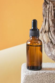 brown glass bottle with a pipette on a concrete podium on a wooden driftwood background, brown background copy space natural cosmetic concept