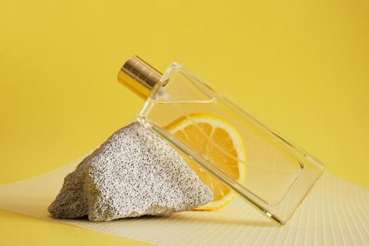 citrus scent, perfume with lemon scent concept, concrete block fragment, lemon slice and bottle of perfume on yellow background