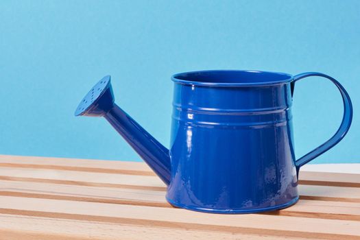 dark blue watering can on a wooden table top view copy space
