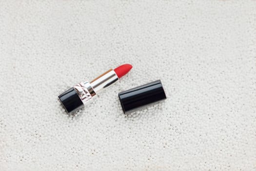 red lipstick on white bubbles with white textured background. flat lay image