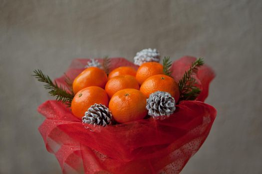 bouquet of mandarins and Christmas tree branches. New Year's edible bouquet of fruits. Gift for Christmas. DIY gift. useful gift made of fruits. decoration of cones and tangerine fruits.