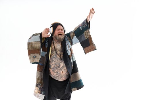 Fat stylish bearded tattoed caucasian man with big belly is posing and dancing wearing ethnic kimono