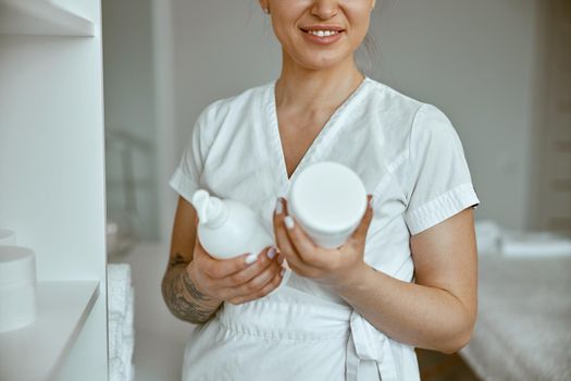 beautiful happy caucasian female masseur is posing in white minimalistic modern treatment salon