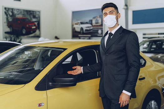 Man car dealer wearing protective medical mask on his working place, coronavirus prevention concept