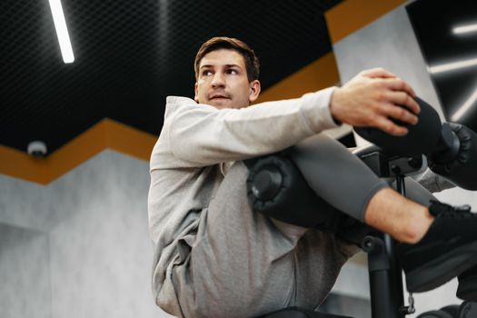 Young athlete doing abs exercises workout in modern gym, close up