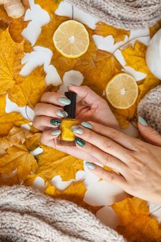 manicure on green and grey nails with black and gold rhinestones with brilliant ornament on girls hand. golden nail polish and manicure