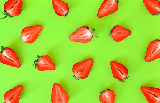 Strawberries pattern close up. Bright pattern of fresh cut in half strawberries on light green background. Top view, flat lay.