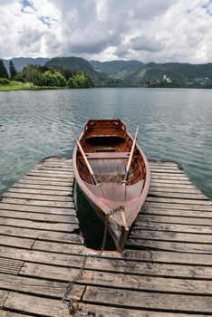 Bled, Slovenia - May 20, 2018: Beautiful Lake Bled in the Julian Alps and old wooden boat. Mountains, tourist boat, lake and dramatic sky.