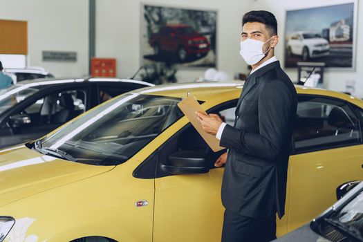 Man car dealer wearing protective medical mask on his working place, coronavirus prevention concept