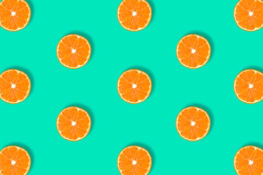 Fruit pattern of fresh mandarin slices isolated on blue or mint background. Flat lay, top view. Pop art design, creative summer concept. Half of tangerine citrus in minimal style.