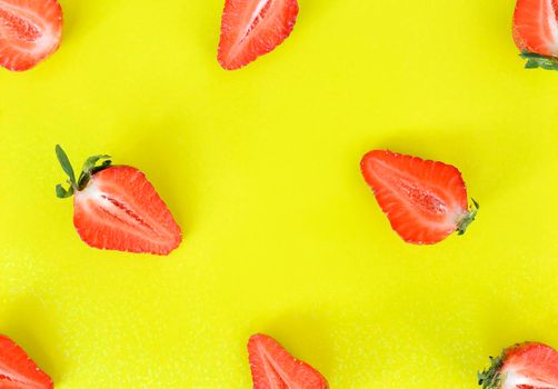 Strawberries pattern close up. Bright pattern of fresh cut in half strawberries on yellow background. Top view, flat lay.