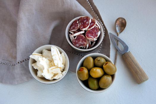Antipasto catering platter with different meat and cheese products. cheese, olives and ham for a simple breakfast. linen napkin and small knife