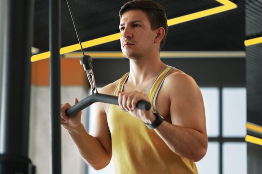 Young bodybuilder doing heavy weight exercise for biceps in a gym, close up