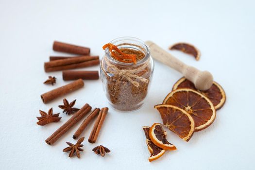 Cinnamon sticks, dried oranges and star anise with brown sugar bottle with shallow depth of field on white background. Baking ingredients for cooking