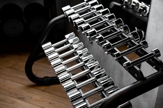Rows of metal dumbbells on rack for bodybuilding in a gym
