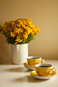 yellow flowers bouquet on the table - Two yellow coffee cups on white background, coffee break and caffeine addiction concept. vintage design and retro style