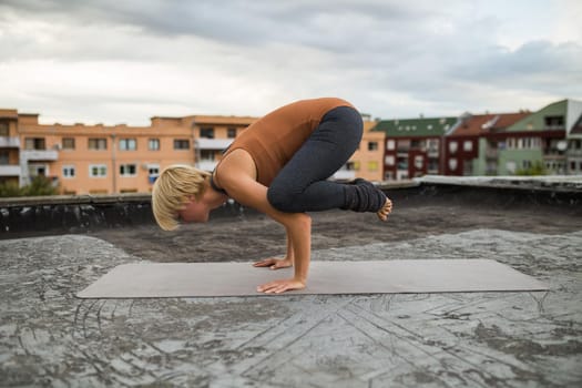 Beautiful woman  enjoys practicing yoga on the roof of a building,Bakasana/Crane Pose.
