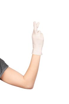 Hand gesture. Hand in a white latex glove showing fingers crossed sign isolated on white background. Hope concept