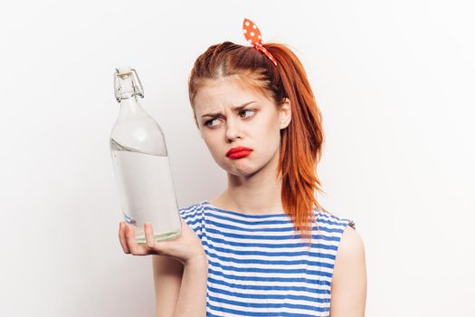 beautiful woman in striped t-shirt with bottle of alcohol light background. High quality photo