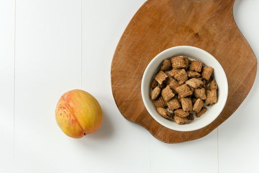 brakefast with chocolate pillows and peach. Crispy cereal and chocolate pillows with milk. wooden table and white background.