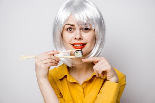 pretty woman in white wig and sushi with Japanese chopsticks. High quality photo
