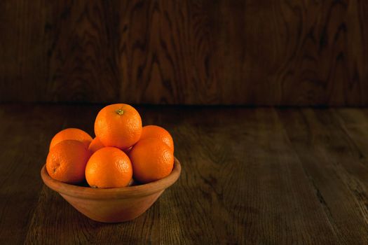 A lot of oranges on the bowl - dark background. Still life fruits in vintage style. Tasty oranges at the bowl dark photo