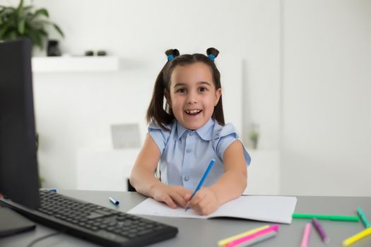 Pretty stylish schoolgirl studying homework math during her online lesson at home, social distance during quarantine, self-isolation, online education concept, home schooler