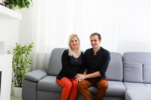 Happy young couple is hugging and smiling while sitting on the couch at the psychotherapist.