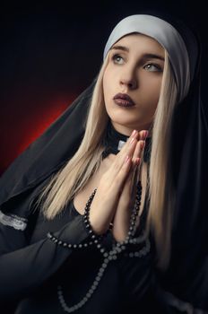 girl on a black background in a nun dress posing with a gun, aiming, shooting