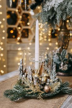 A candle in a candlestick decorated in a Christmas theme. A decor concept for home decoration for the New Year holidays, table decoration for Christmas.