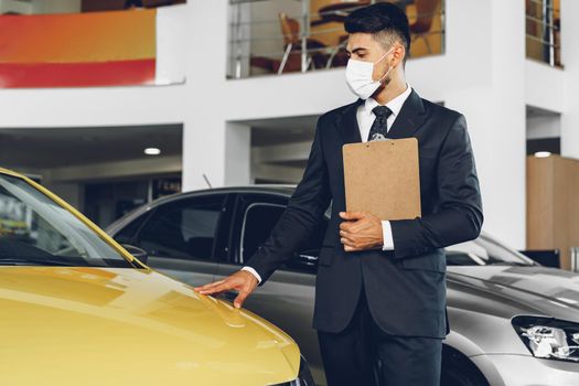 Man car dealer wearing protective medical mask on his working place, coronavirus prevention concept