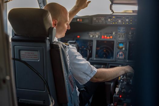 Focused professional pilot sitting in an airplane cabin, ready for takeoff. Aircraft, aircrew, occupation concept