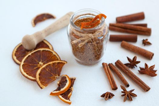 Cinnamon sticks, dried oranges and star anise with brown sugar bottle with shallow depth of field on white background. Baking ingredients for cooking