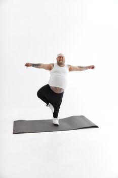 Sporty fat man with beard and tattoos is doing yoga