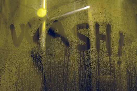 The inscription on the soap glass - wash. WASH letters on the shower glass-handwritten lettering written on gray stuface with water drops