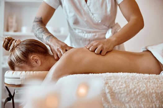 Professional confident massage master is doing procedures to caucasian woman in minimalistic modern cabinet