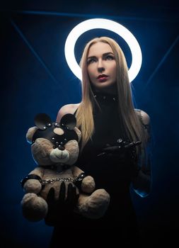 the woman with a halo in black clothes with a tattoo machine and a toy bear
