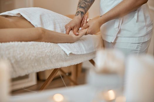 Professional confident massage master is doing procedures to caucasian woman in minimalistic modern cabinet