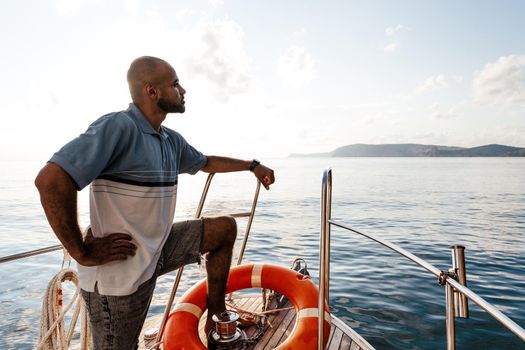 Young african american man relaxing on a sailboat in open sea at sunset, close up