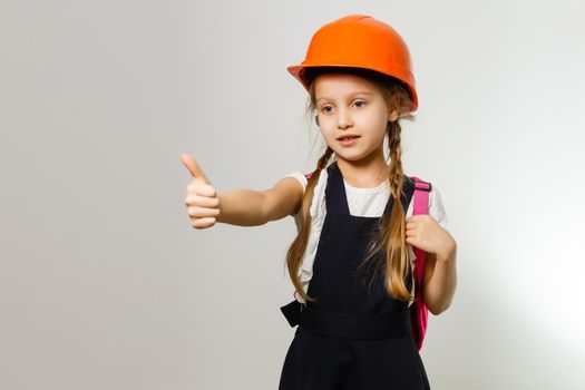 Cute little girl is isolated on white background. Girl looking at camera, wearing yellow helmet