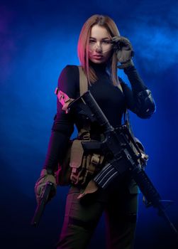 the woman in military airsoft uniform with an American automatic rifle and pistol on a dark background