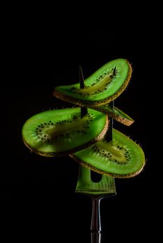 Sliced fresh and juicy green kiwi on the silver fork on dark background. healthy food concept. close up. low key. 4