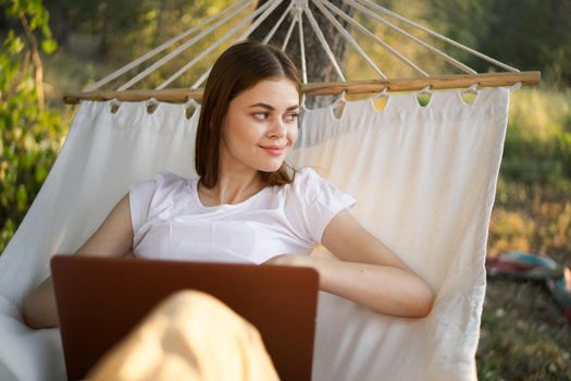 woman working in front of laptop in a hammock in nature. High quality photo