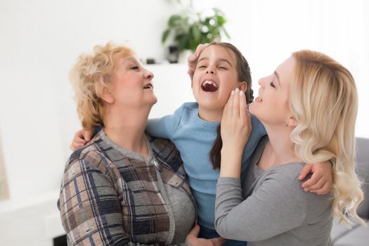 Portrait of three generations of women look at camera posing for family picture, cute little girl hug mom and granny enjoy time at home, smiling mother, daughter and grandmother spend weekend together